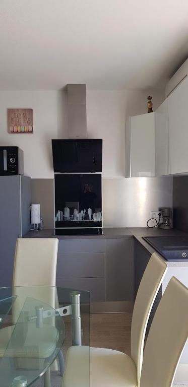 une cuisine avec une table en verre et deux chaises dans l'établissement Le MINOU, à Roquebrune-Cap-Martin