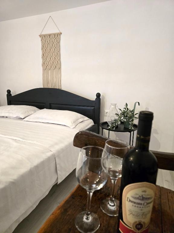 a bedroom with a bed and two wine glasses on a table at Casa tradițională Eridav in Arcani