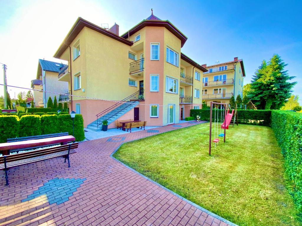 a building with a yard with a bench and a playground at Podlesie in Ostrowo