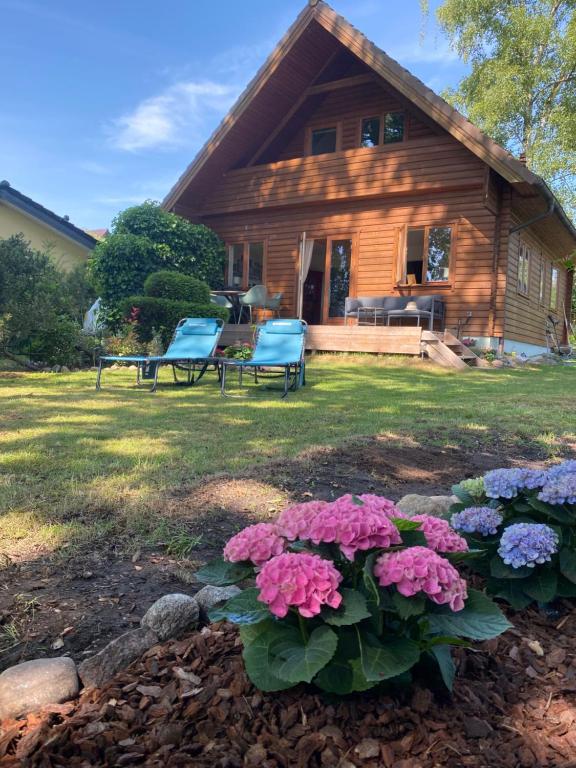 a house with two chairs and flowers in the yard at Uferglück Plau - mit eigenem Seezugang in Plau am See