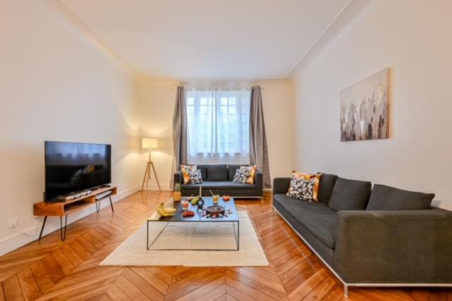 un salon avec un canapé et une télévision dans l'établissement Elegant appartement 3 chambres, 3 salles de bain- Double séjour- Paris 16e- Calme et standing, à Paris