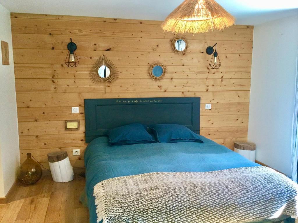 une chambre avec un lit bleu avec un mur en bois dans l'établissement Chambres de charme, à Lège-Cap-Ferret