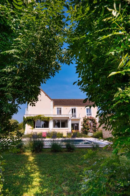 une maison vue à travers les arbres dans l'établissement Terre de Partages, à Saint-Bris-le-Vineux