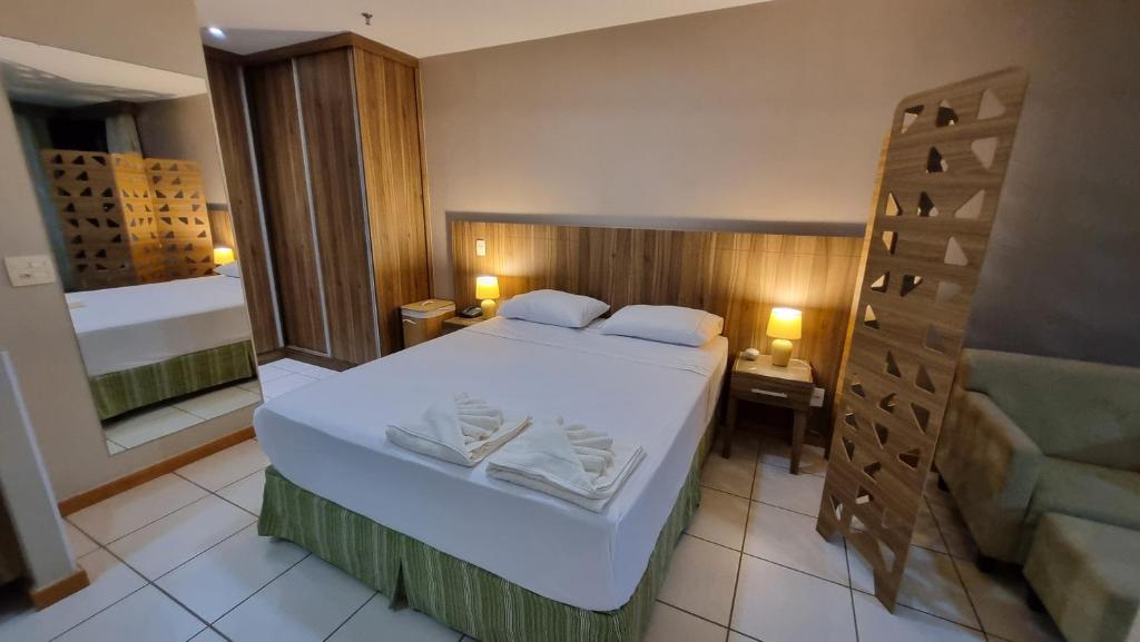 a bedroom with a large bed with white sheets at ApartHotel no Centro de Brasília in Brasilia