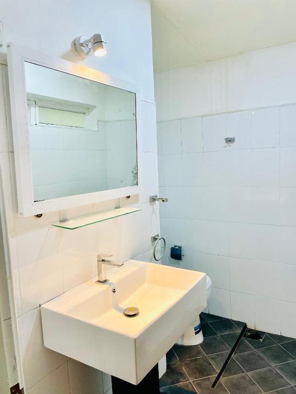a white bathroom with a sink and a mirror at Heavenly Horizon Villa in Kandy