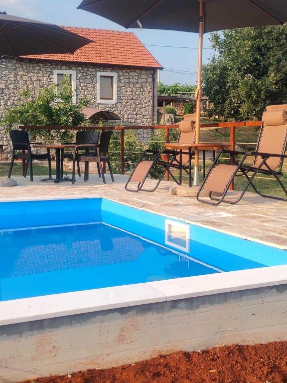 a swimming pool with a table and chairs and an umbrella at Old House Piperi in Podgorica