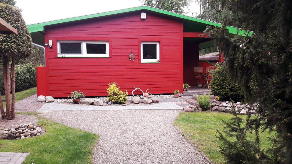 a red shed with a white window and a patio at Ferienhausidylle mit Motorboot und Kanu in Basedow