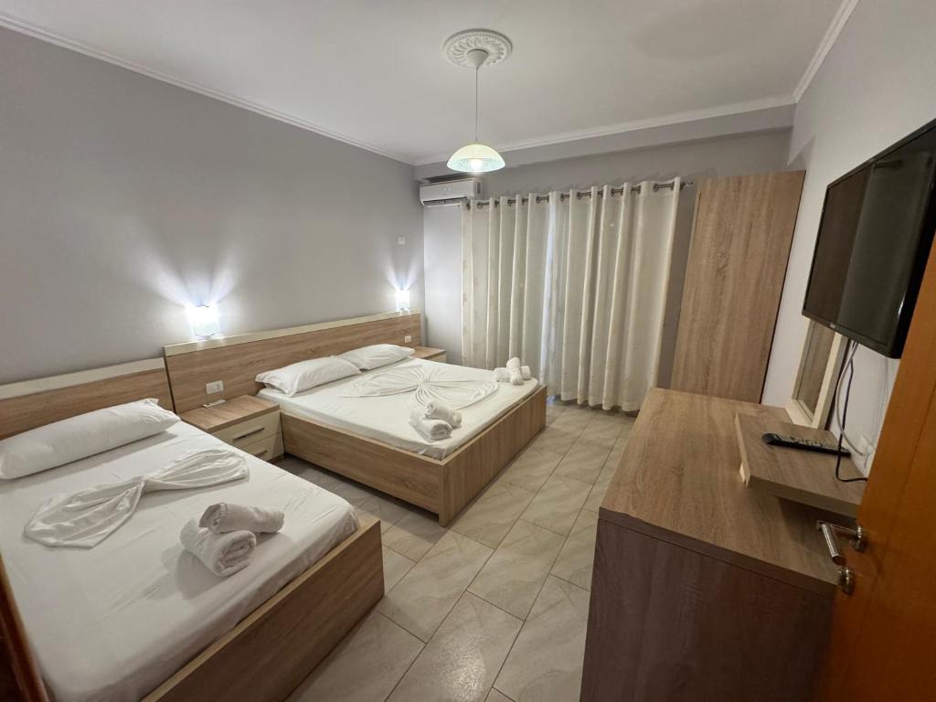 a bedroom with two beds and a flat screen tv at Augustus Hotel in Dhërmi