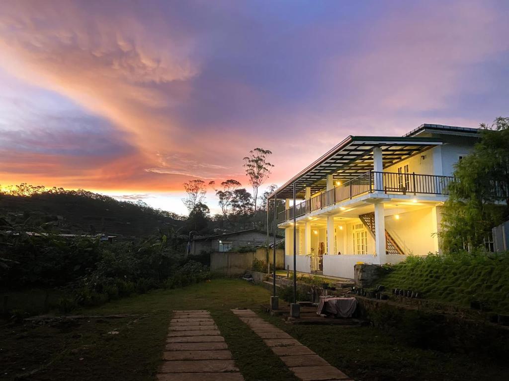 een wit huis met een zonsondergang op de achtergrond bij Lavender Villas Nuwara Eliya in Nuwara Eliya
