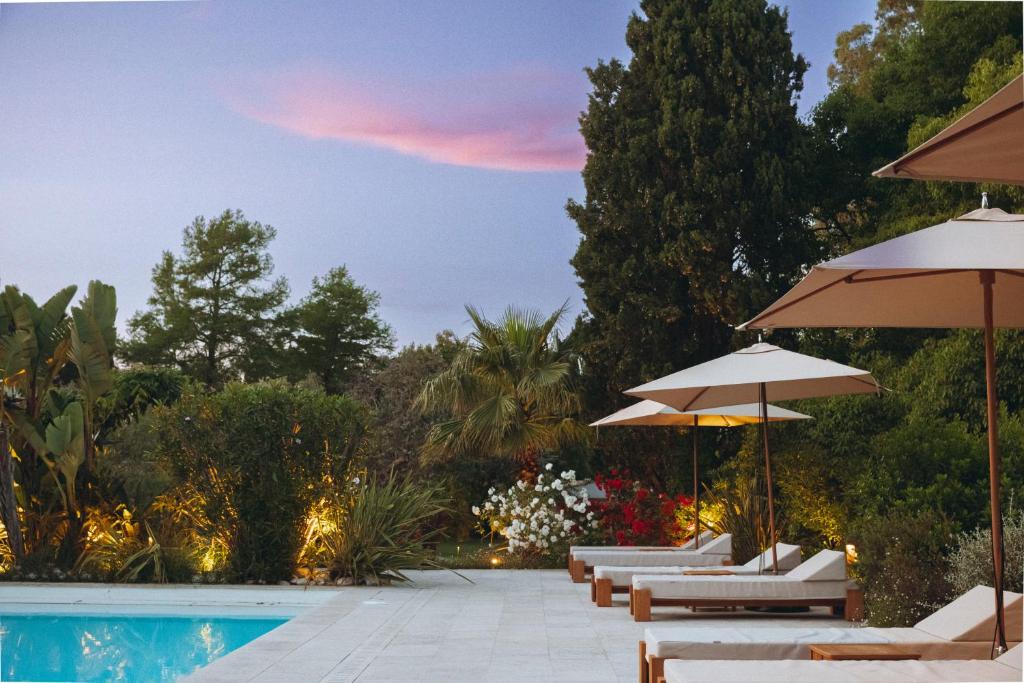 a resort pool with umbrellas and lounge chairs at La Bastide des Salins in Saint-Tropez