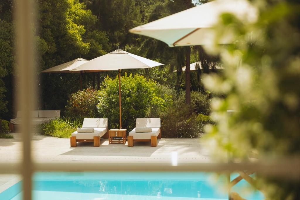 two chairs and an umbrella next to a pool at La Bastide des Salins in Saint-Tropez