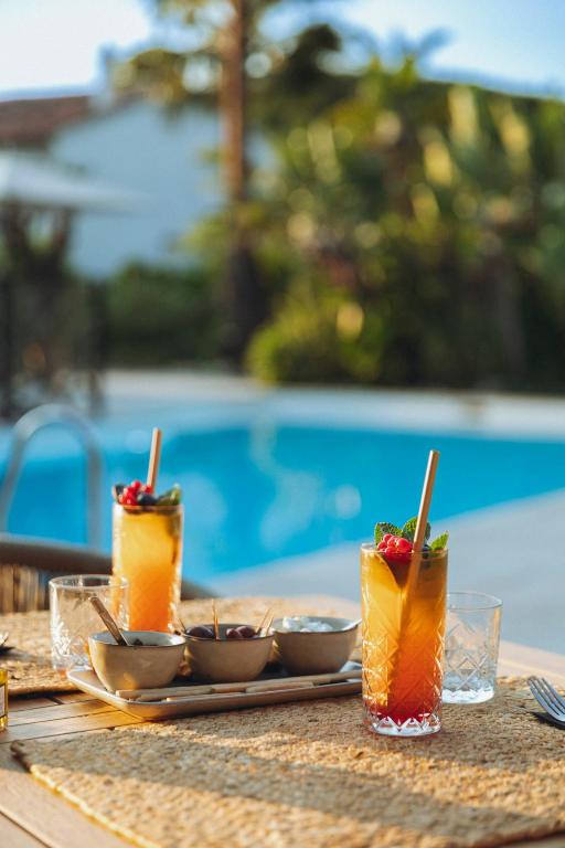 a table with three drinks on a table near a pool at La Bastide des Salins in Saint-Tropez