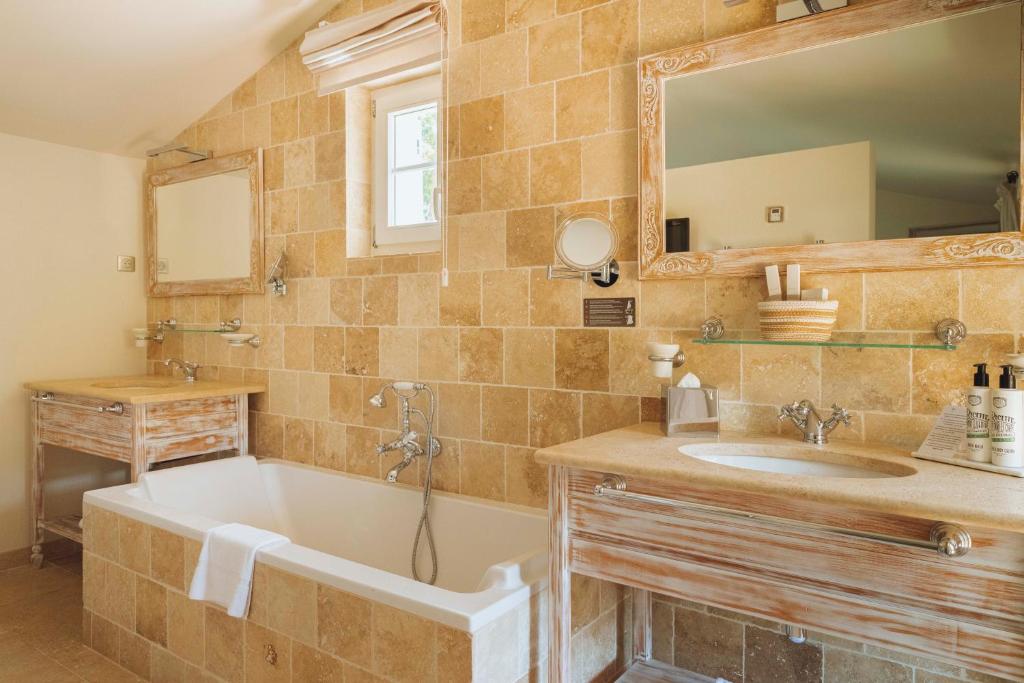 a bathroom with a tub and a sink and a mirror at La Bastide des Salins in Saint-Tropez