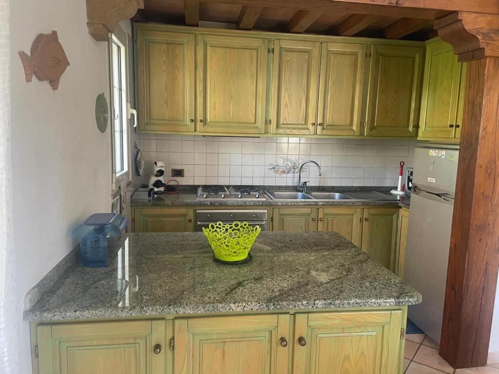 a kitchen with wooden cabinets and a green bowl on a counter at Maison Linda in Santa Teresa Gallura