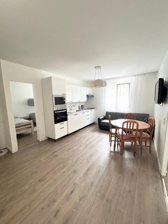 un salon avec une table et des chaises et une cuisine dans l'établissement appart idéal en famille parking privé, à Drancy