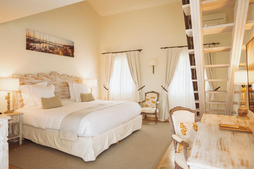 a bedroom with a large white bed and a ladder at La Bastide des Salins in Saint-Tropez
