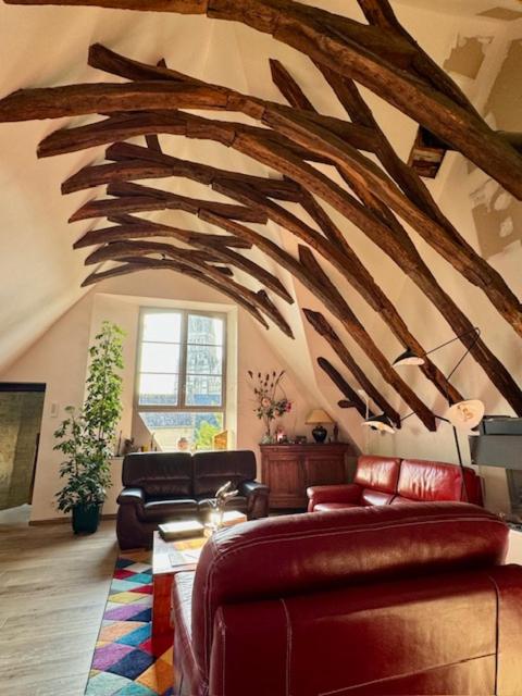 Elle comprend un salon doté d'un mobilier en cuir et d'un grand plafond en bois. dans l'établissement LA MAITRISE, à Bayeux