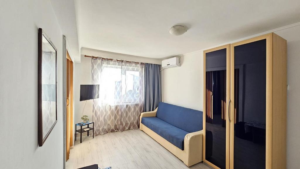 a living room with a blue couch and a window at To the Nerversea beach! in Constanţa