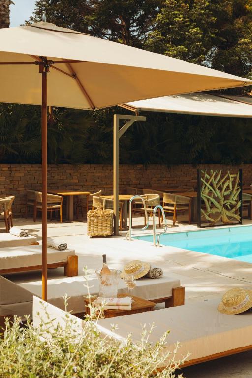 a large tan umbrella over a swimming pool at La Bastide des Salins in Saint-Tropez