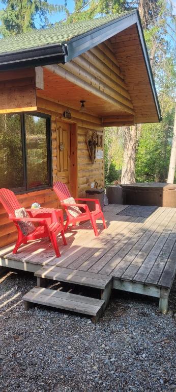 a wooden deck with red chairs and a cabin at Beautiful Cabin near Radium Hot Springs with private hot tub in Radium Hot Springs