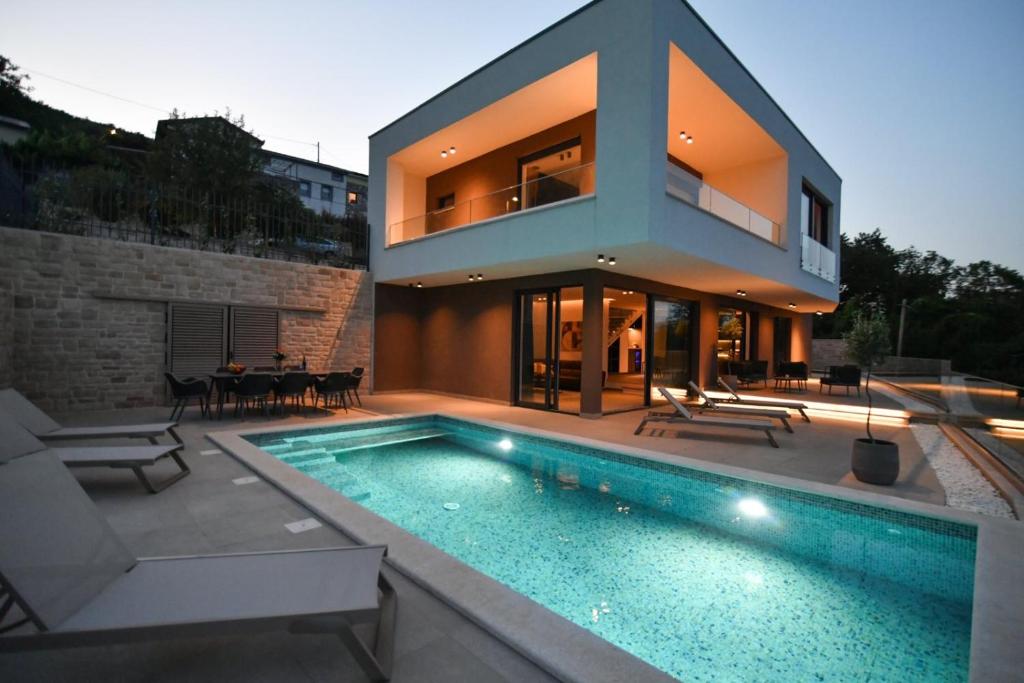 a house with a swimming pool in front of a house at Villa Marmonte, Luksuzna vila s bazenom i pogledom na more in Medveja