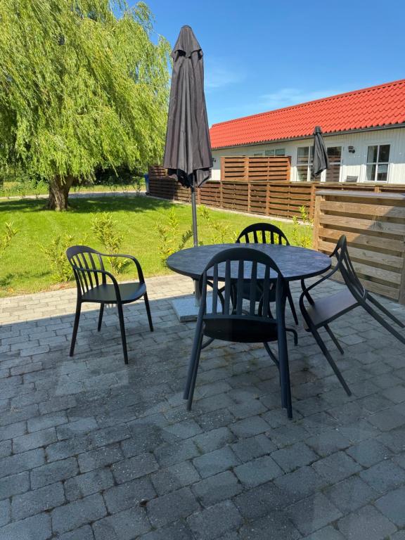 a table and two chairs and an umbrella on a patio at Bøtø strand ferielejlighed 4 in Marielyst