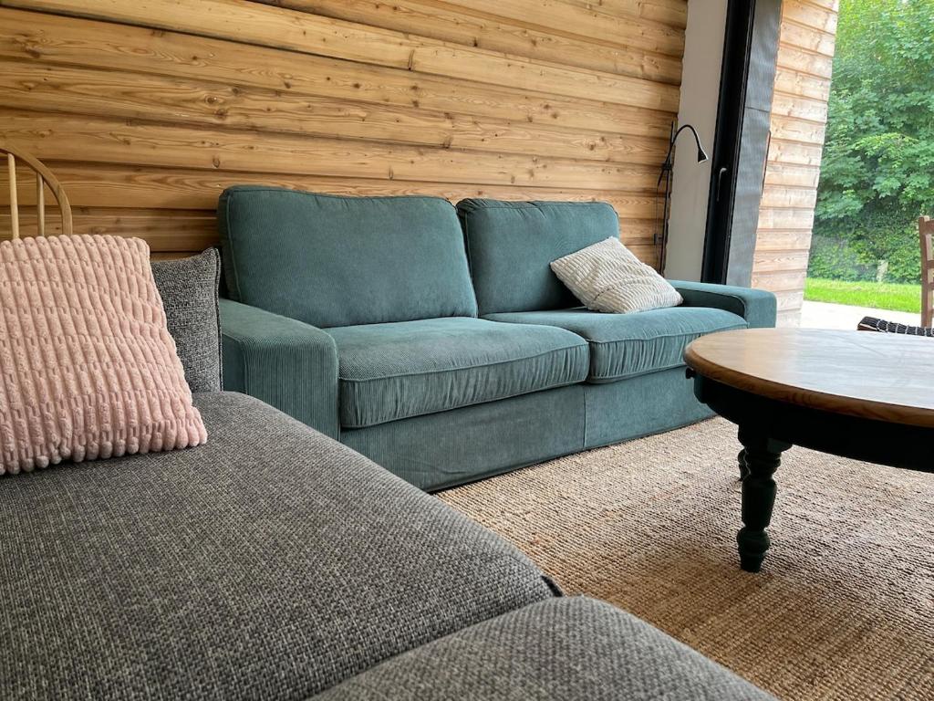 a blue couch in a living room with a table at Maison Osithe in Doudeauville
