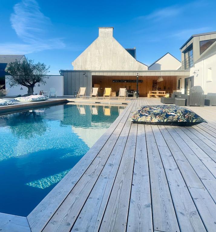 une piscine avec une terrasse en bois à côté d'une maison dans l'établissement Villa le 25 - Piscine et Sauna au bourg de Carantec, à Carantec