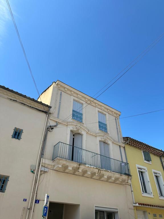 un bâtiment blanc avec un balcon au-dessus dans l'établissement Appartement centre du village, à Nissan-lez-Enserune