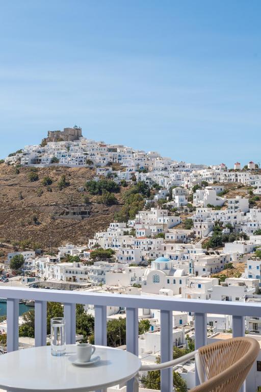 a table on a balcony with a view of a city at Korali in Astypalaia