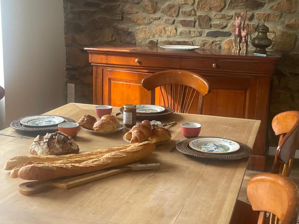 a table with bread and plates of food on it at Parenthèse à la Maison de l'Ecrivain entre nature et petit déjeuner festin in Servon