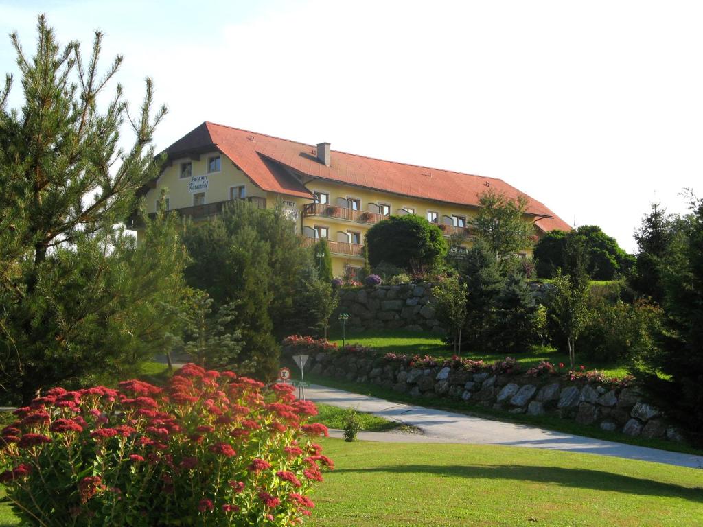 a large house with a stone wall and flowers at Dreilandhof in Loipersdorf bei Fürstenfeld
