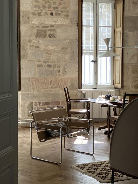 d'une salle à manger avec des chaises, une table et un mur en briques. dans l'établissement Maison Thaïs, deux pièces de charme, à Autun