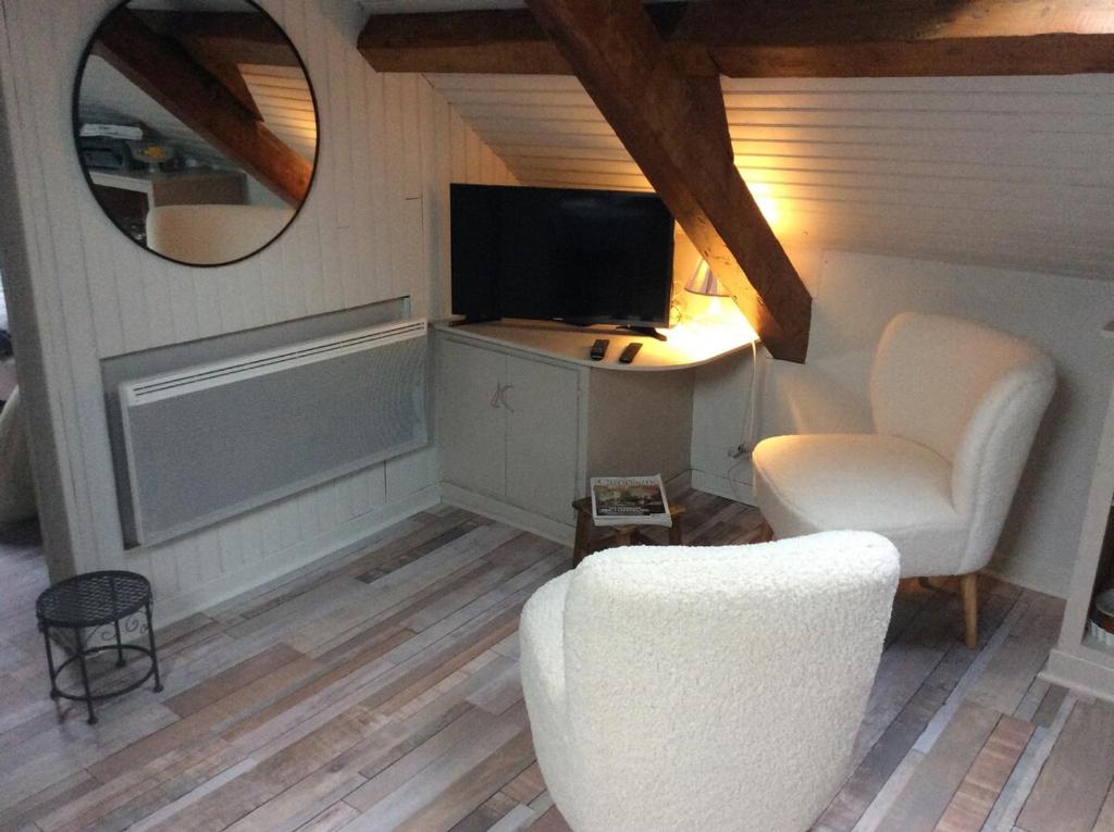 un soggiorno con sedia bianca e TV di Toit et Moi a Le Mont-Dore