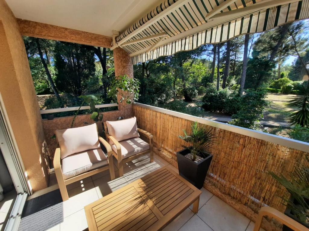 - un balcon avec deux chaises, une table et un banc dans l'établissement Appartement 2 CH résidence calme et arborée , proximité plages et commerces, à Toulon