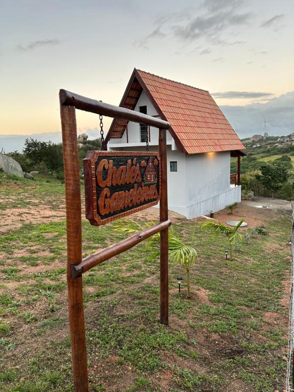 a sign in a field in front of a building at Chalé Gameleiras in Monte das Gameleiras