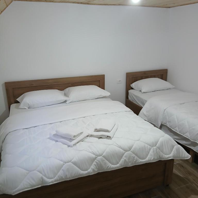 two beds with white sheets and a pair of shoes on them at Bujtina Sherifaj in Valbonë