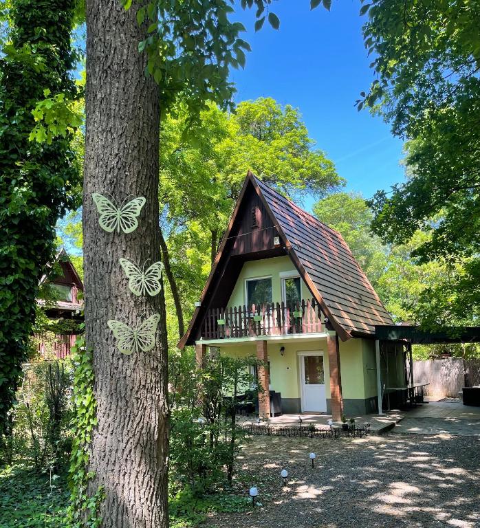 a small house with butterflies painted on a tree at Zöld Éden Kabin in Makó
