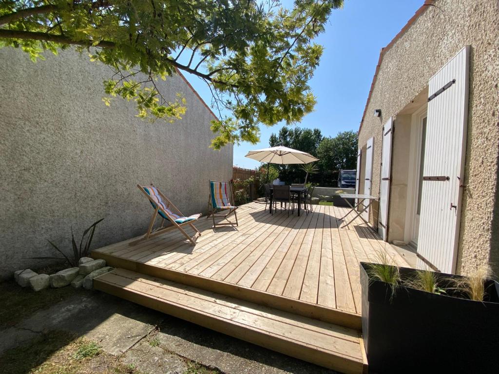 une terrasse en bois avec deux chaises et un parasol dans l'établissement Maison Île d'Oléron - 6 personnes 3 chambres, au Château-dʼOléron