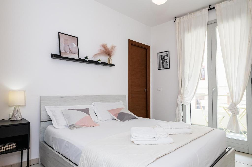 a white bedroom with a large bed and a window at Appartment - Joile Maisone in Porto Torres