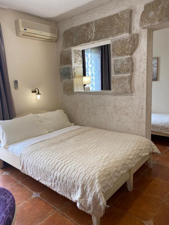 a bed in a bedroom with a stone wall at Hotel Villa Perla Di Mare in Budva