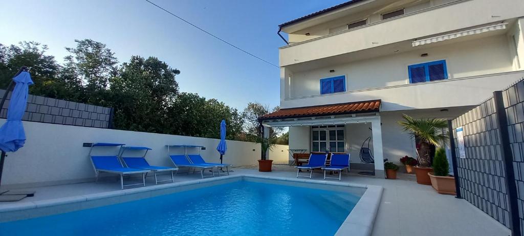 a swimming pool with blue chairs next to a building at VILLA BIANCA - Holiday home with Private pool in Privlaka