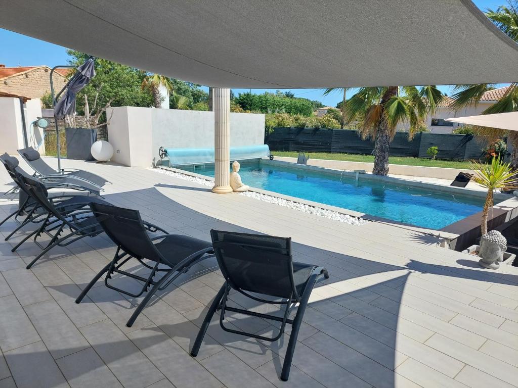 un patio avec des chaises et un parasol à côté d'une piscine dans l'établissement Villa 6 personnes piscine chauffée, à Saint-Aunès