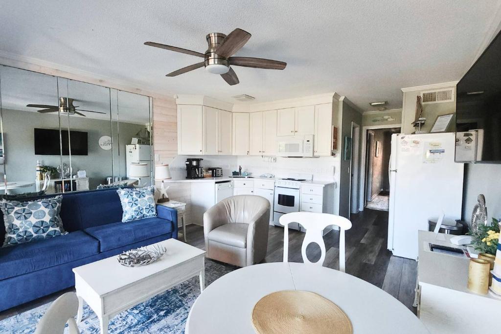 a living room with a blue couch and a kitchen at Salty Air & Sea Breezes in Hilton Head Island