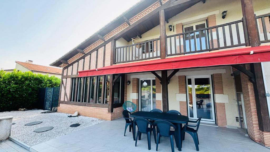 a patio with black tables and chairs in front of a building at Le Mas des Cerisiers in Le Temple-sur-Lot