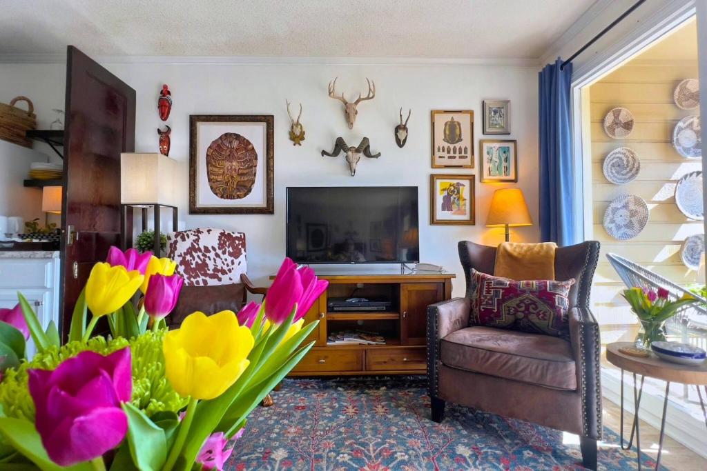 a living room with a tv and flowers in a room at Dunes with Design in Hilton Head Island