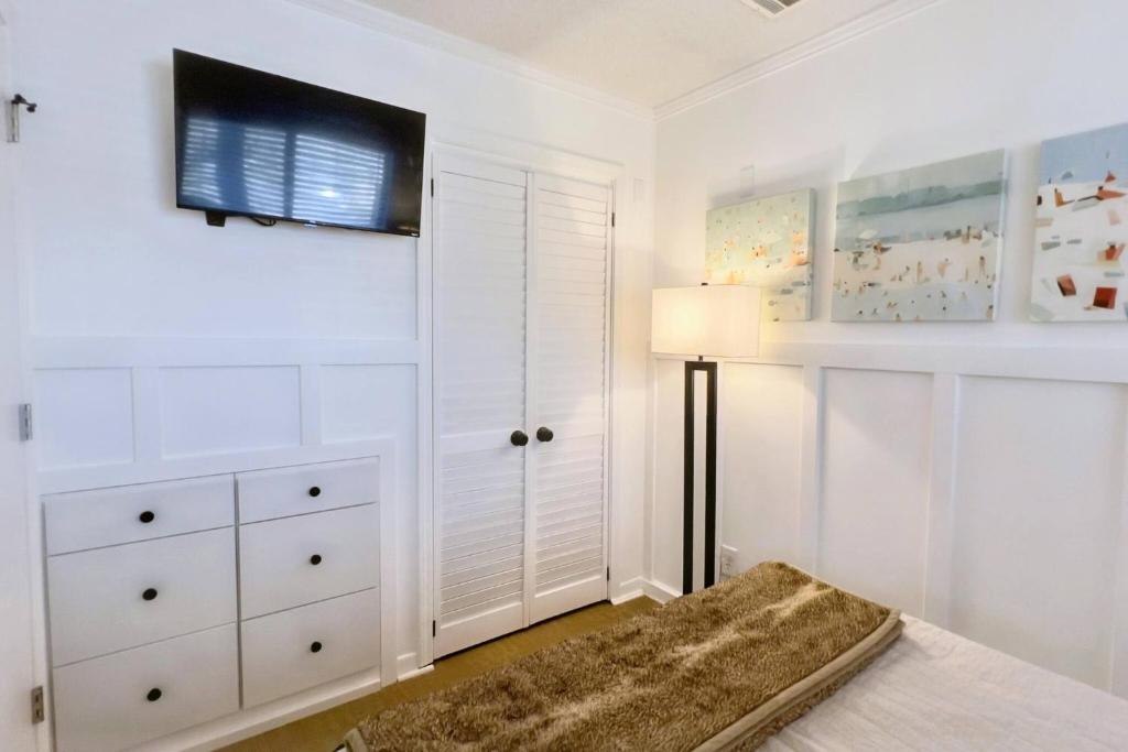 a bedroom with white walls and a tv on the wall at Dunes with Design in Hilton Head Island