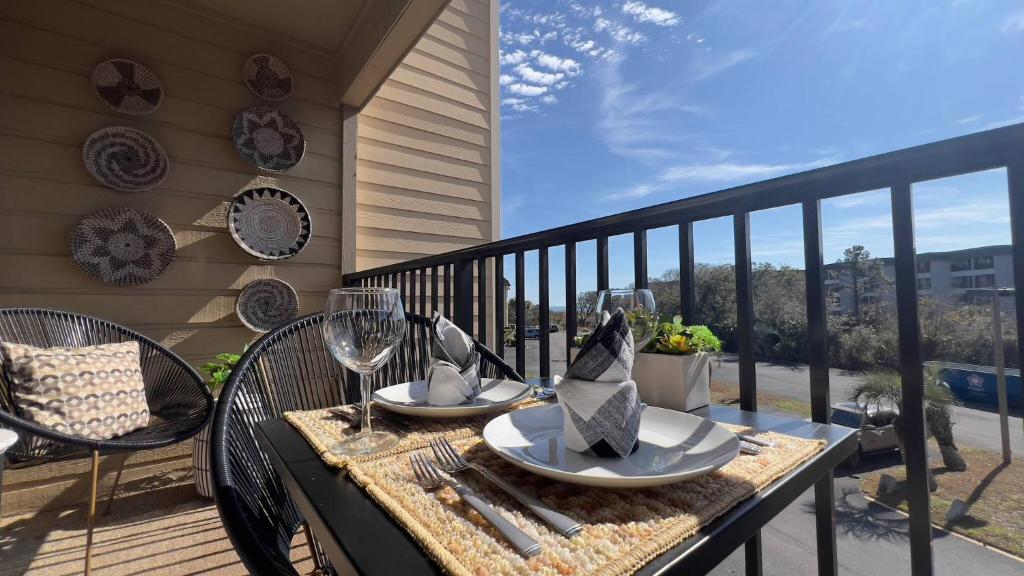 a table with plates and wine glasses on a balcony at Dunes with Design in Hilton Head Island