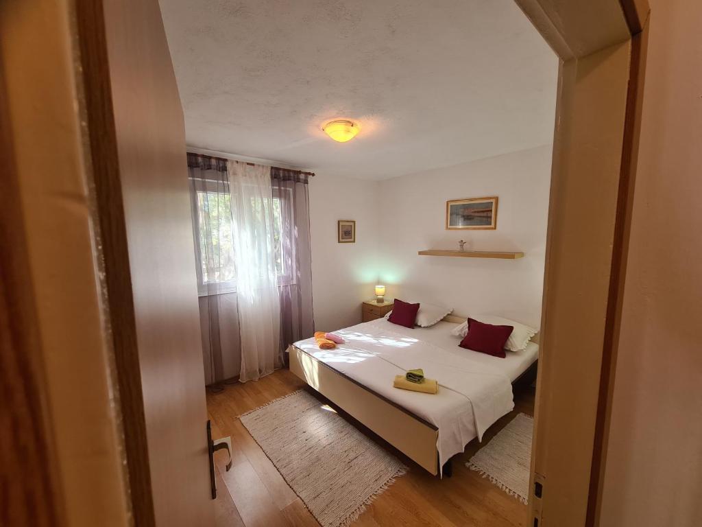 a small bedroom with a bed and a window at Apartmani Uvodić in Rogoznica