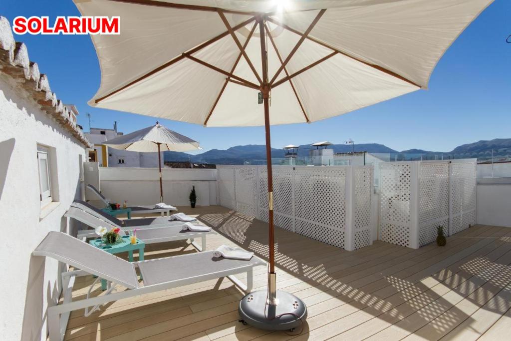 a patio with chairs and an umbrella on a roof at Hotel El Tajo & SPA in Ronda